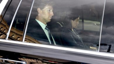 Mark Zuckerberg and Sheryl Sandberg in a car, reflecting a building.