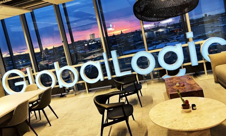 GlobalLogic logo illuminated in a modern office lounge with city view at dusk.