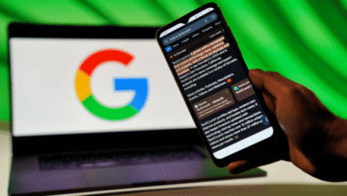 A hand holds a smartphone displaying Google AI Overviews search results next to a laptop with the Google logo.