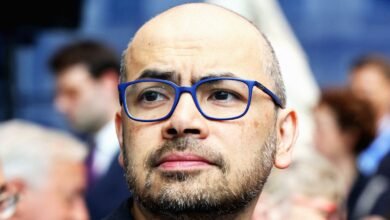 Close-up of a man with a beard wearing blue-rimmed glasses.