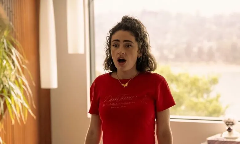Rachel Sennott in red t-shirt with surprised expression indoors.