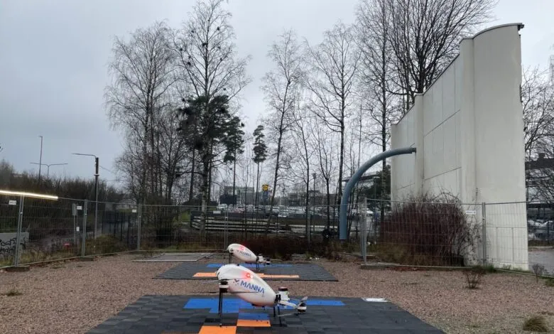 Two Manna delivery drones on landing pads in an outdoor setting.
