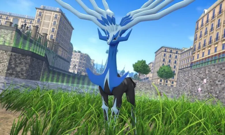 Xerneas, a legendary Pokémon, stands in a city park with tall grass.
