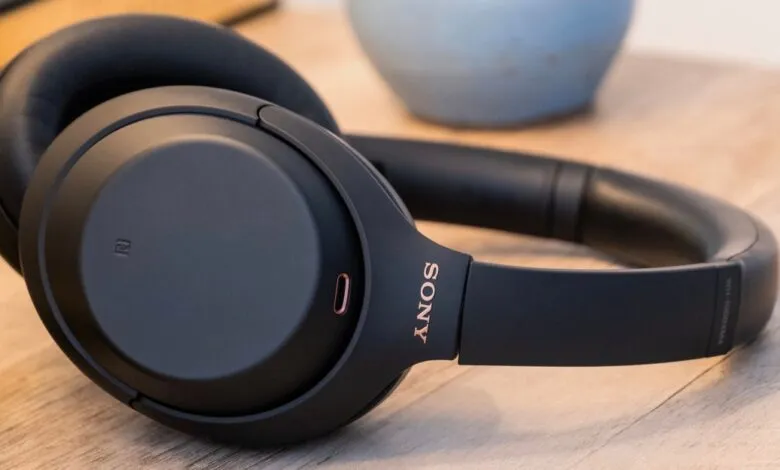 Black Sony WH-1000XM4 noise-canceling headphones on a wooden surface.