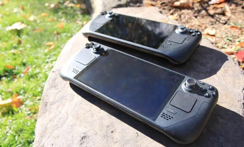 Two black handheld gaming consoles resting on a large rock outdoors.