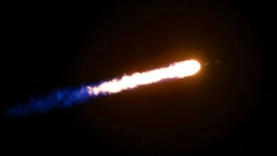 A rocket trail with bright orange and white flames against a black sky.