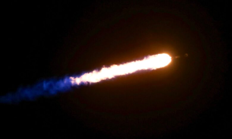 A rocket trail with bright orange and white flames against a black sky.