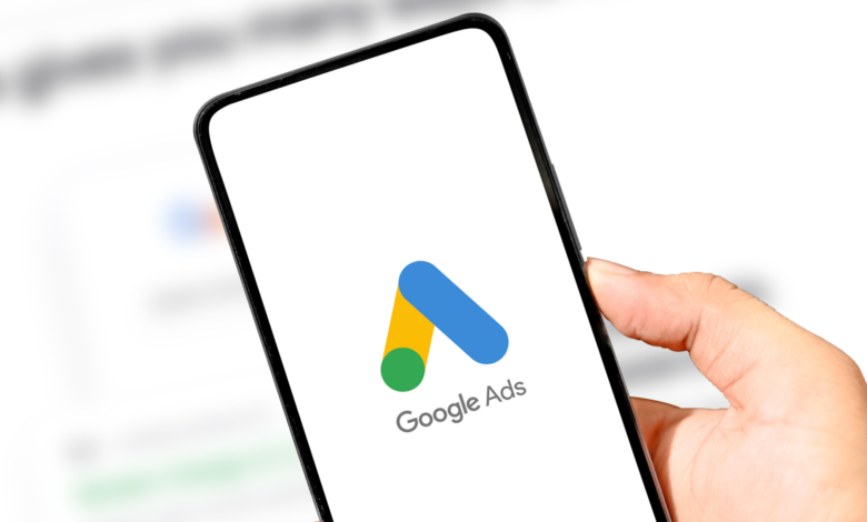 Close-up of a hand holding a smartphone displaying the Google Ads logo.