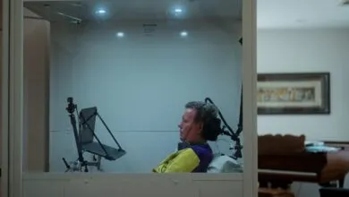 Man in accessible booth with laptop, assistive tech, looking forward.