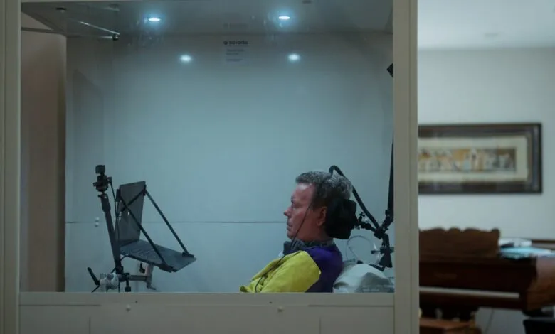 Man in accessible booth with laptop, assistive tech, looking forward.