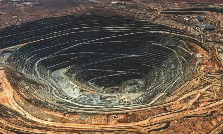 Aerial view of a massive open-pit mine with terraced layers and winding roads.