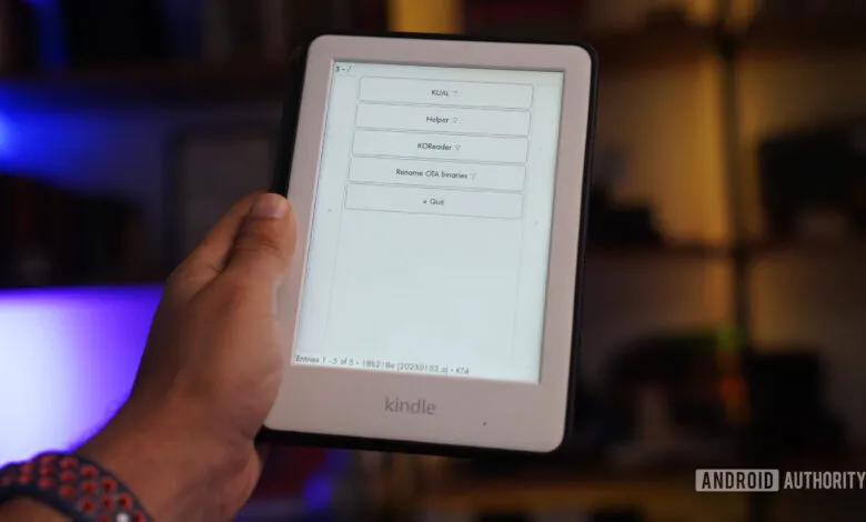 Hand holding a jailbroken Kindle displaying a menu with KUAL, Helper, KORecder, and Quit options.