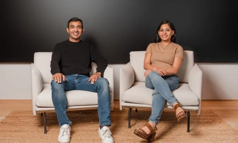 A man and a woman sit in modern armchairs against a dark background.