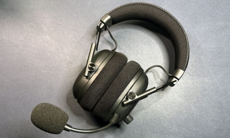 Black over-ear headphones with a boom microphone resting on a textured gray surface.