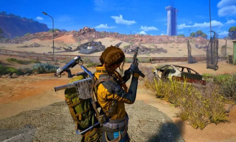 A woman in a yellow jacket with a backpack and guns stands in a post-apocalyptic desert landscape.