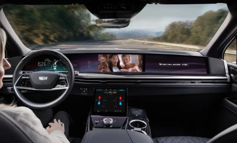Interior view of a Cadillac Escalade IQ with a large curved display showing navigation and entertainment.