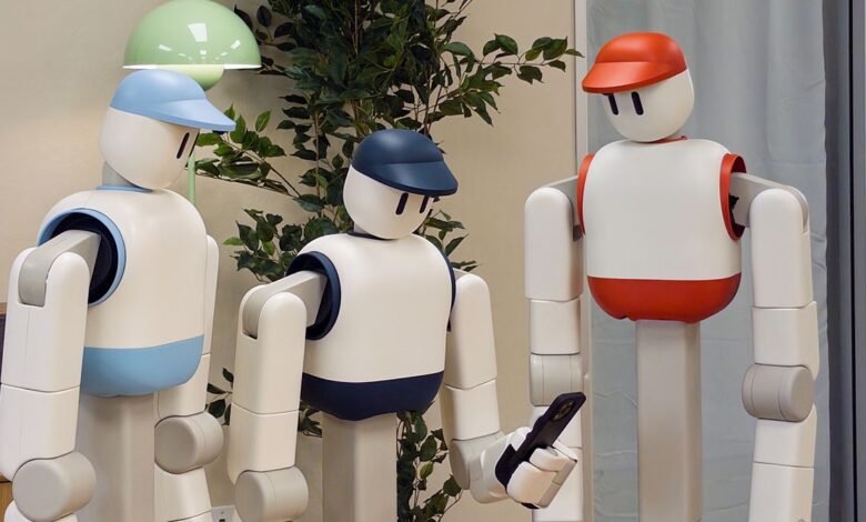 Three robots wearing baseball caps, one holding a smartphone.
