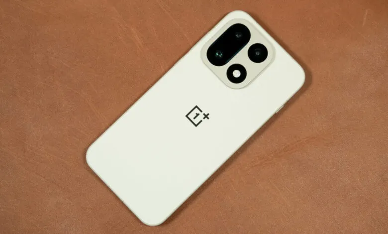 Close-up of a white OnePlus smartphone with a distinctive camera module on a textured brown surface.