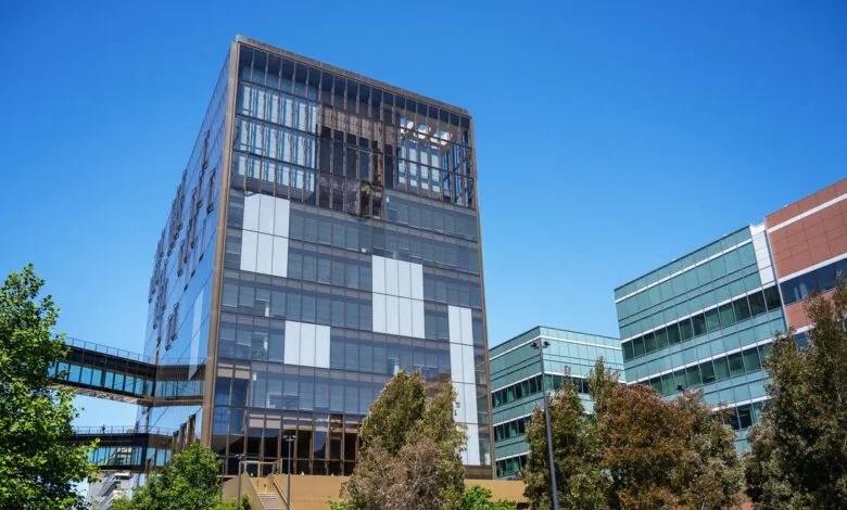 Modern office buildings with glass facades and skybridges on a sunny day.
