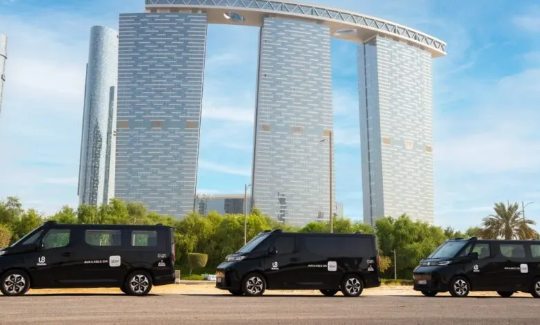 Three black vans parked in front of modern skyscrapers in Abu Dhabi.