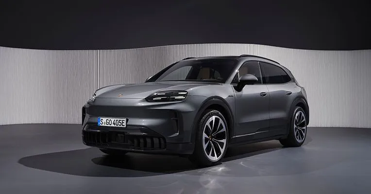 A sleek, dark gray Porsche Cayenne SUV parked indoors with a ribbed wall backdrop.
