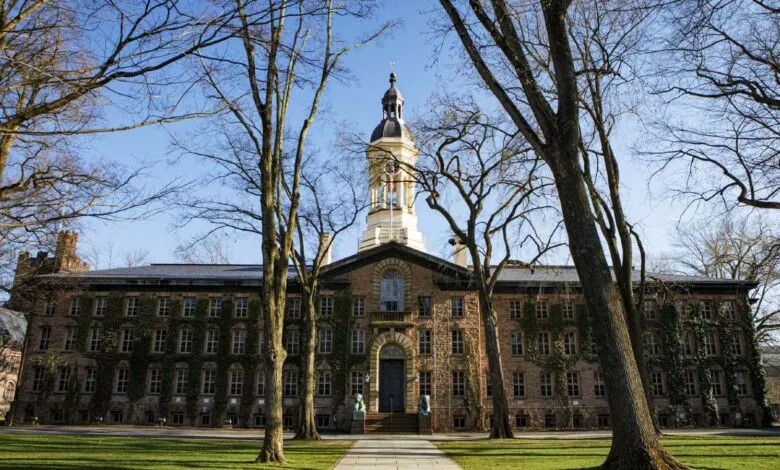 Ivy-covered stone building with a central tower and bare trees in the foreground.