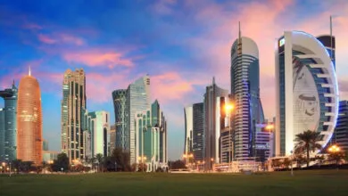 Doha skyline with modern skyscrapers and a grassy park at sunset