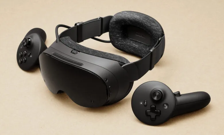 Black virtual reality headset and two controllers on a textured beige background.
