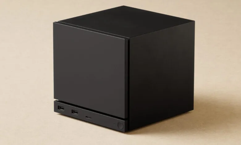 A sleek, black cubic computer or media device with USB ports and a power button.