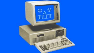 Retro computer with a smiley face on its screen against a vibrant blue background.