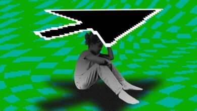 A person sits with their head in their hands under a large pixelated computer cursor.