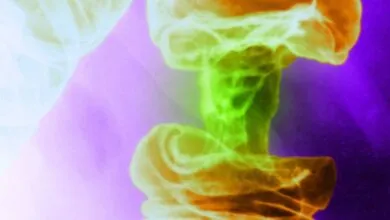 Abstract image of a mushroom cloud in vibrant green, orange, and purple hues.