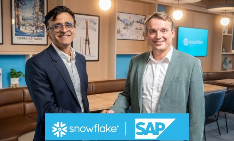 Two men in suits shaking hands in front of Snowflake and SAP logos.
