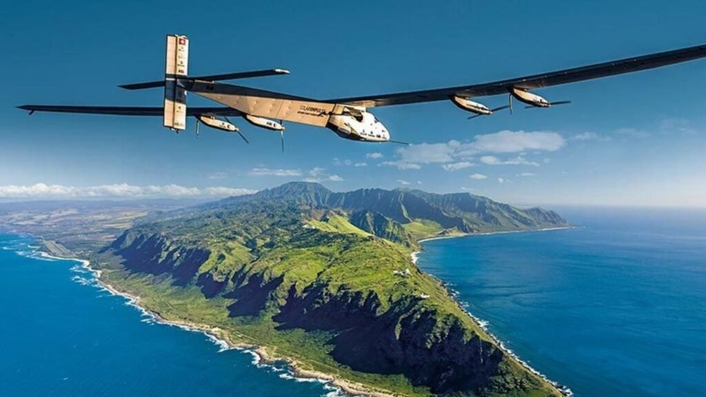 Solar Impulse 2 airplane flying over a lush green coastline with mountains.