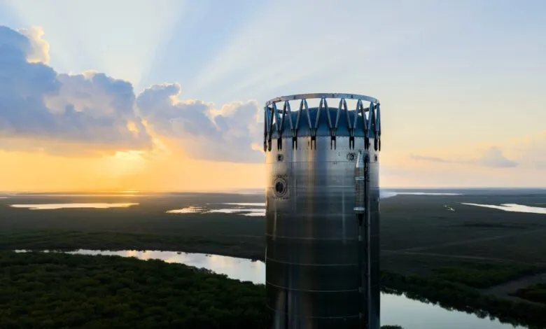 SpaceX Starship rocket stands tall against a sunset sky, surrounded by wetlands.