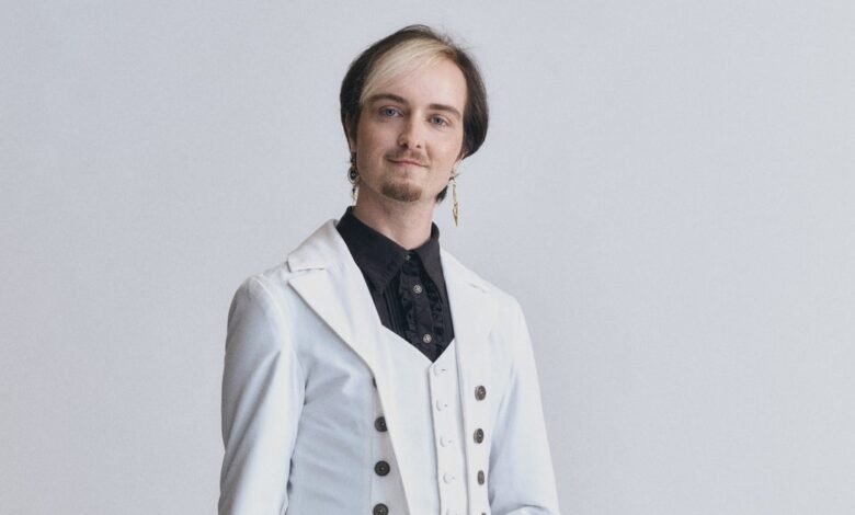Portrait of Stanley Baxton in a white suit against a light gray background.