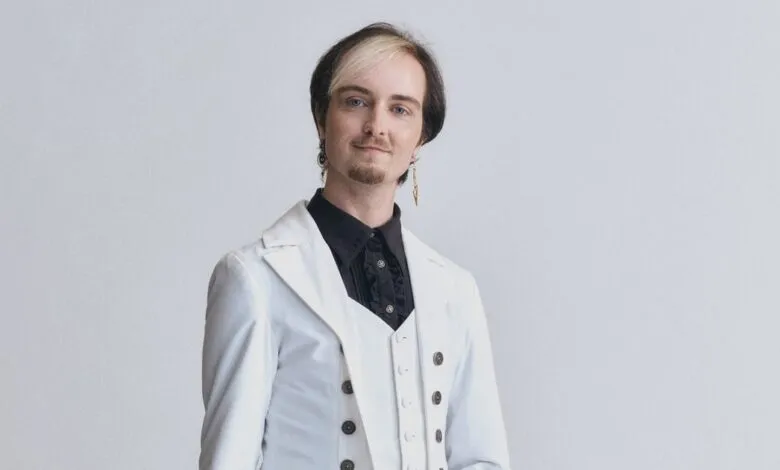 Portrait of Stanley Baxton in a white suit against a light gray background.