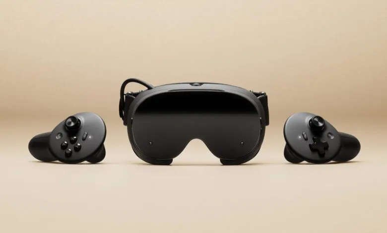Black virtual reality headset with two controllers on a beige background.