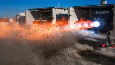 Rocket engine test firing with bright flames and debris flying.