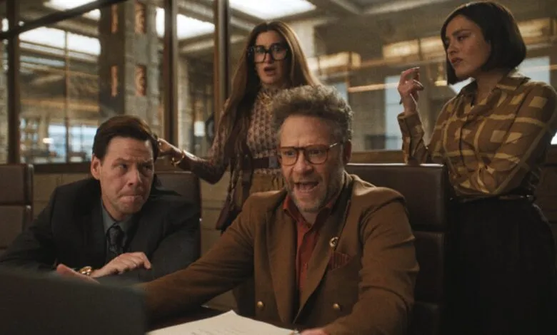 Four people in a meeting, including Seth Rogen, with varied expressions.