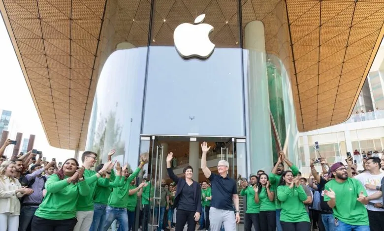 Tim Cook and Deirdre O'Brien wave to a crowd outside an Apple Store.