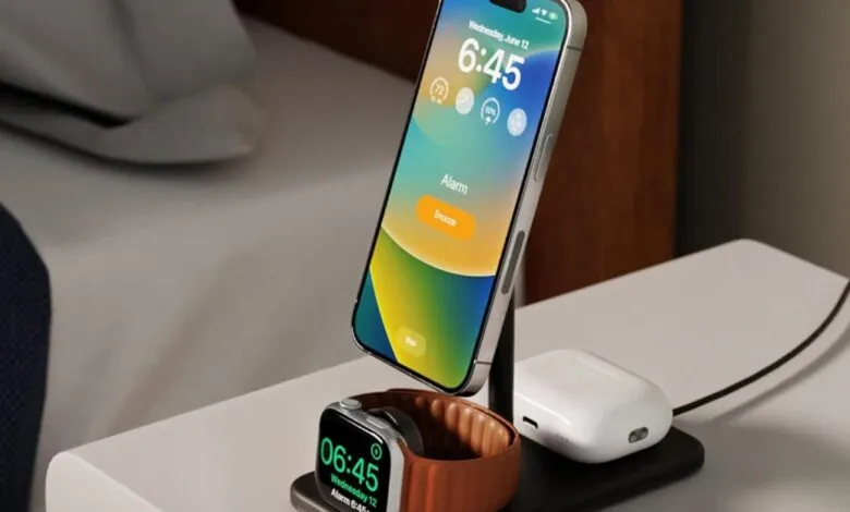 Charging stand with iPhone, Apple Watch, and AirPods on a bedside table.
