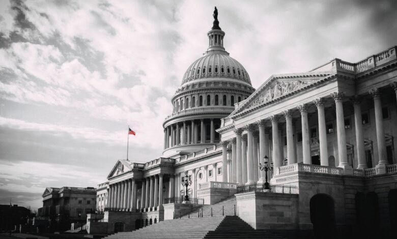 The United States Capitol Building with its dome and columns, under a cloudy sky.