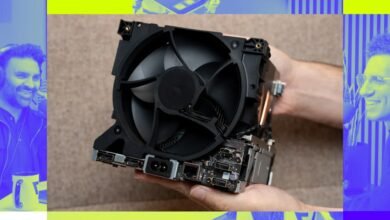 Close-up of a computer CPU cooler with a fan, held by a hand.