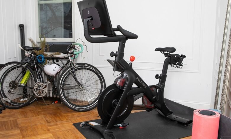 Peloton bike and two bicycles in a room with hardwood floors.