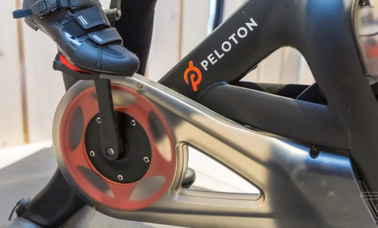 Close-up of a black cycling shoe clipped into a Peloton bike pedal.