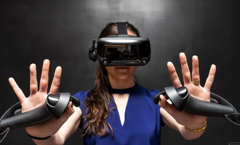 Woman wearing a VR headset and holding controllers, with hands outstretched.