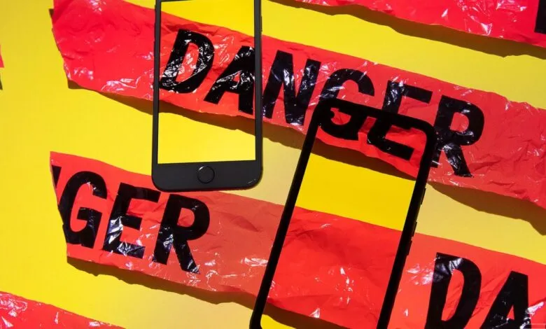 Two smartphones placed on red caution tape with the word DANGER printed in black.