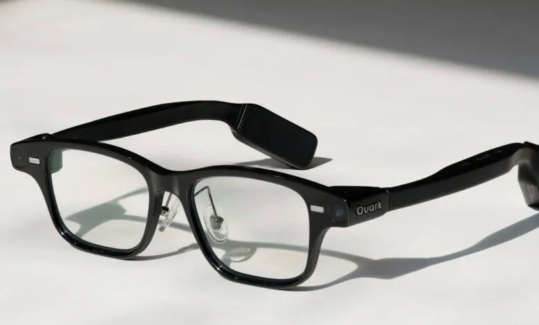 Black Quark smart glasses with clear lenses on a white surface.