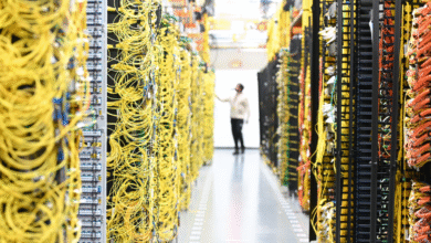 A person in a data center inspecting rows of yellow network cables.